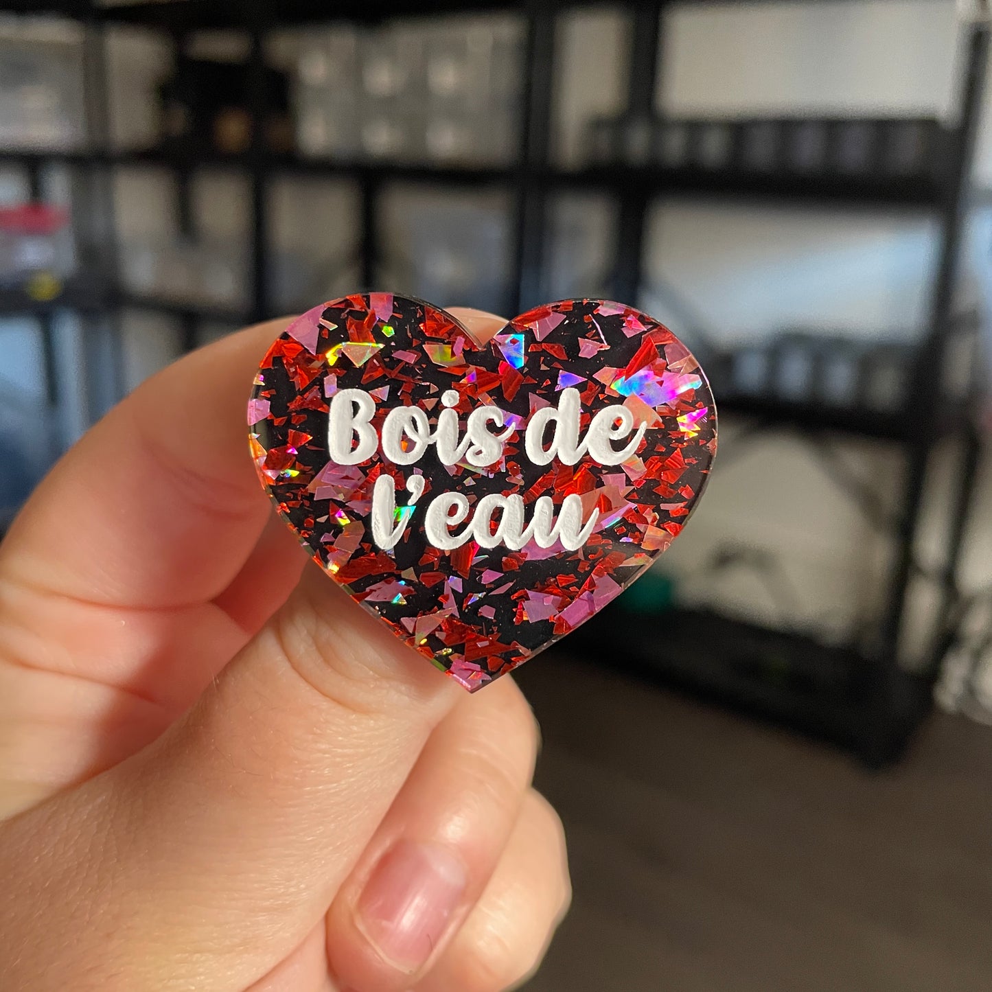 Broche "Bois de l'eau" en acrylique noire avec des éclats de confettis rouges et roses