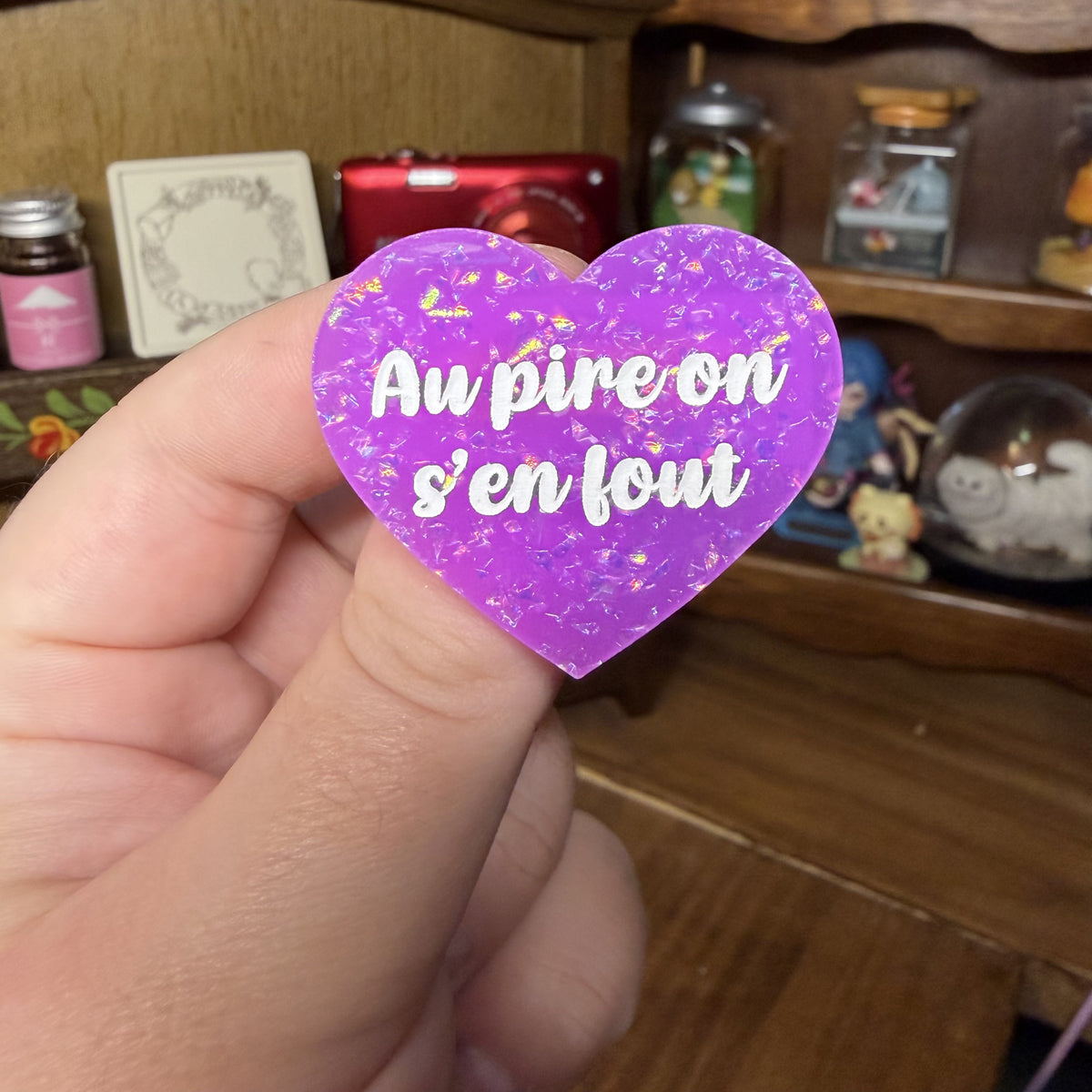 Broche "Au pire on s'en fout" en acrylique violette avec des paillettes holographiques
