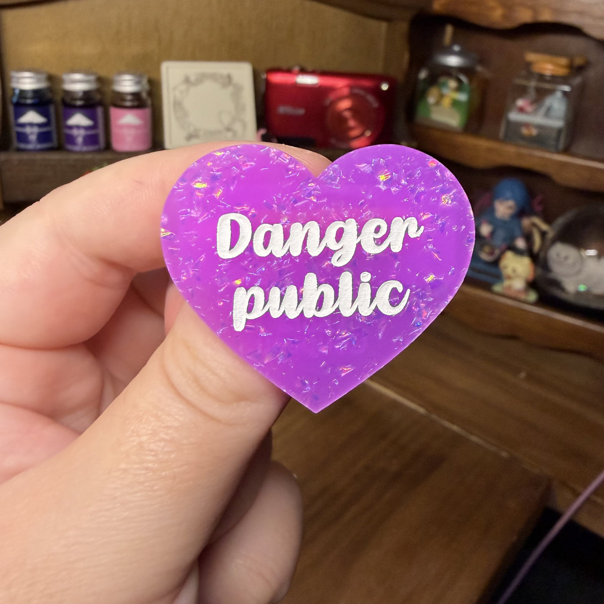Broche "Danger public" en acrylique violette avec des paillettes holographiques