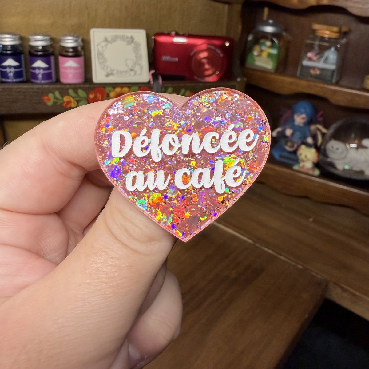 Broche "Défoncée au café" en acrylique semi transparente avec des paillettes corail