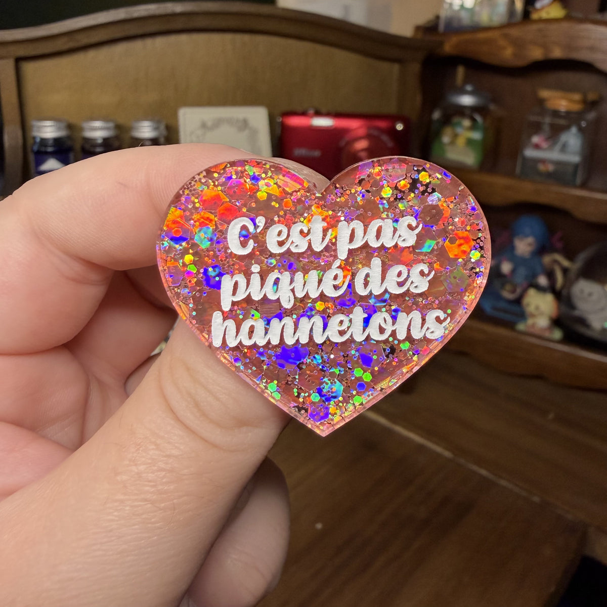 Broche "C'est pas piqué des hannetons" en acrylique semi transparente avec des paillettes corail