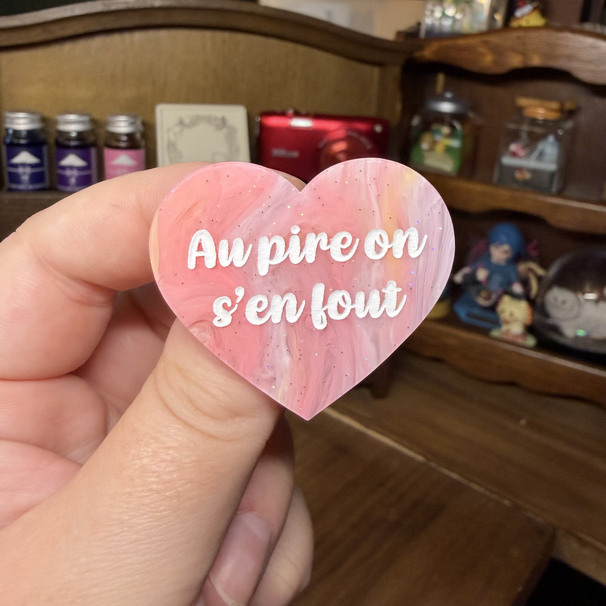 Broche "Au pire on s'en fout" en acrylique marbrée corail, jaune et blanche à paillettes