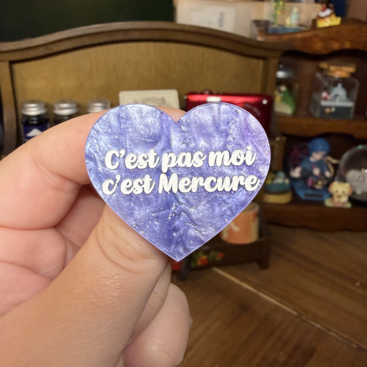 Broche "C'est pas moi c'est Mercure" en acrylique marbrée violette, rose et blanche à paillettes