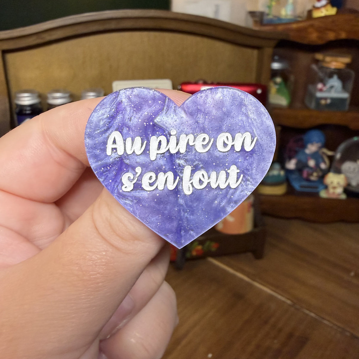 Broche "Au pire on s'en fout" en acrylique marbrée violette, rose et blanche à paillettes