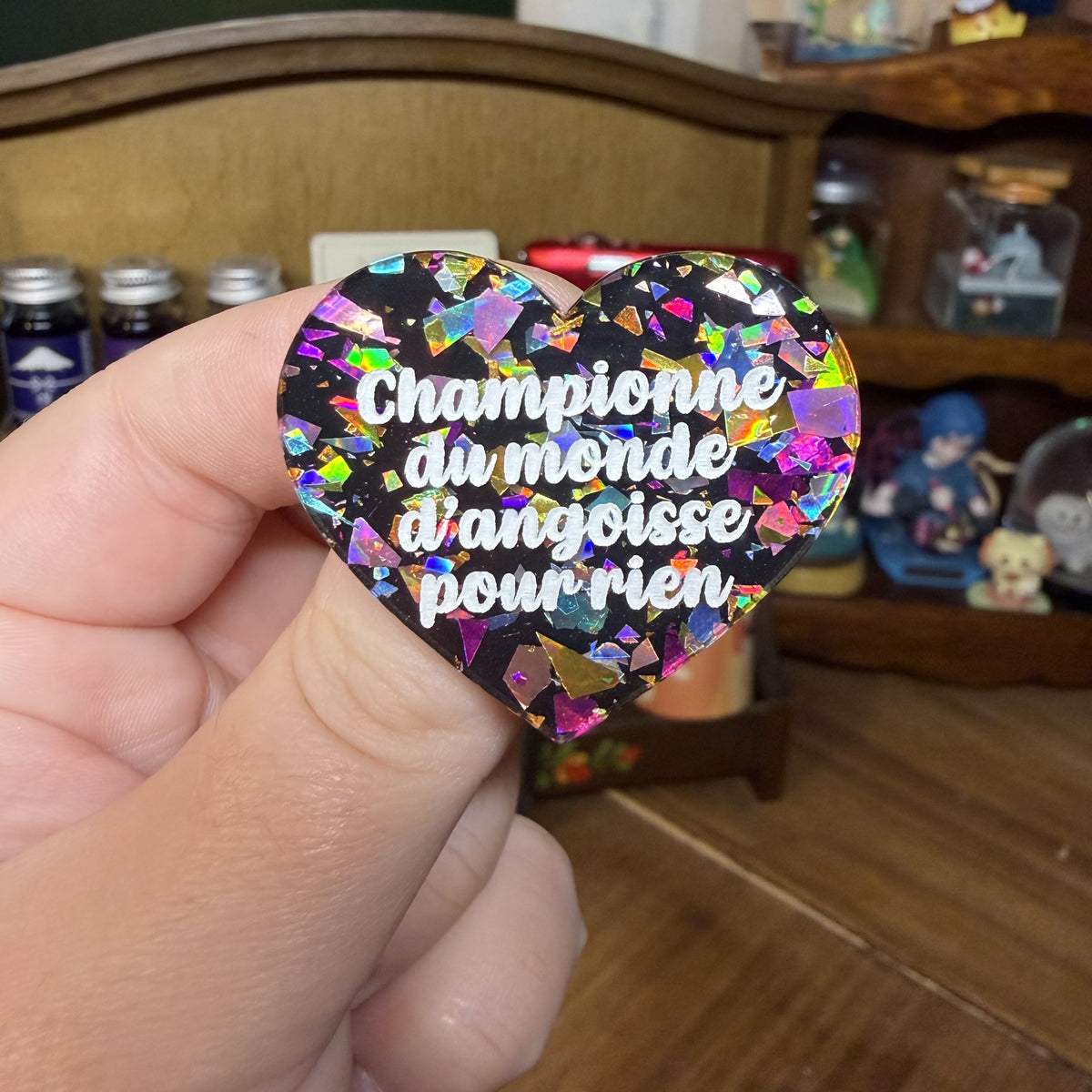 Broche "Championne du monde d'angoisse pour rien" en acrylique noire avec des éclats de confettis multicolores