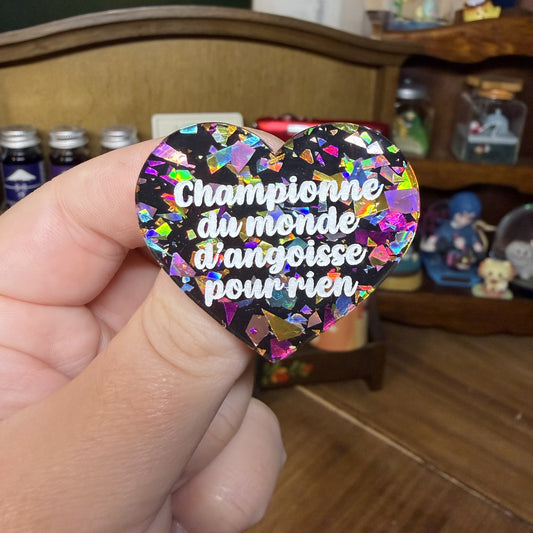 Broche "Championne du monde d'angoisse pour rien" en acrylique noire avec des éclats de confettis multicolores