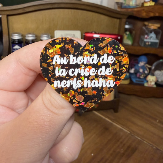 Broche "Au bord de la crise de nerfs haha" en acrylique noire avec des éclats de confettis oranges