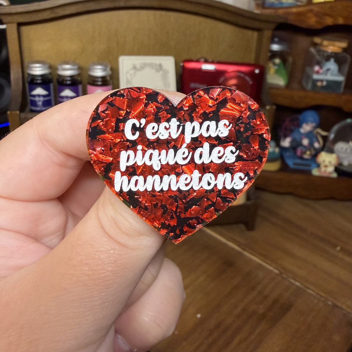 Broche "C'est pas piqué des hannetons" en acrylique noire avec des éclats de confettis rouges