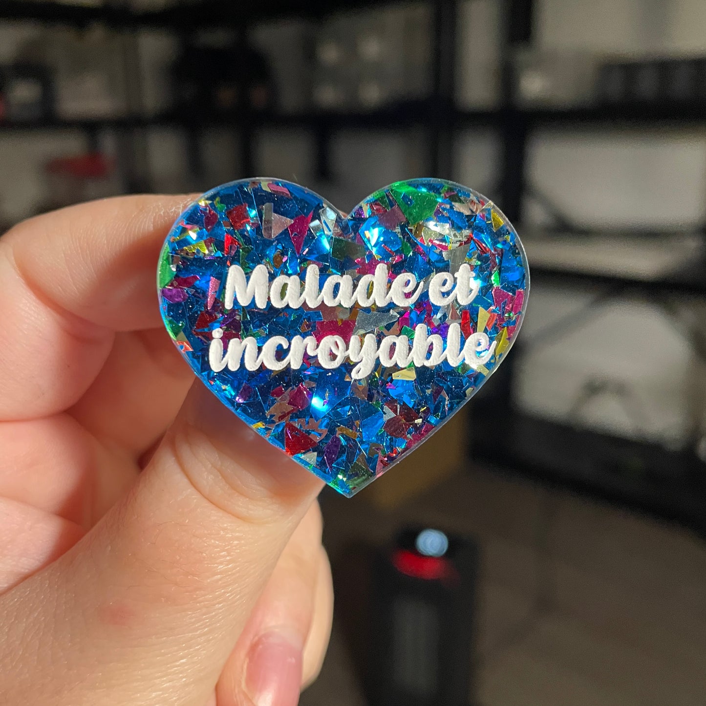 Broche "Malade et incroyable" en acrylique transparente avec des confettis bleus et multicolores