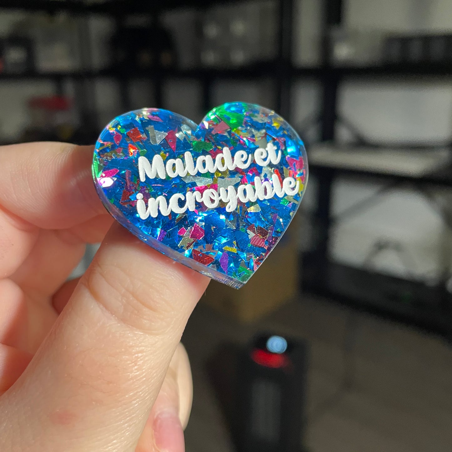 Broche "Malade et incroyable" en acrylique transparente avec des confettis bleus et multicolores
