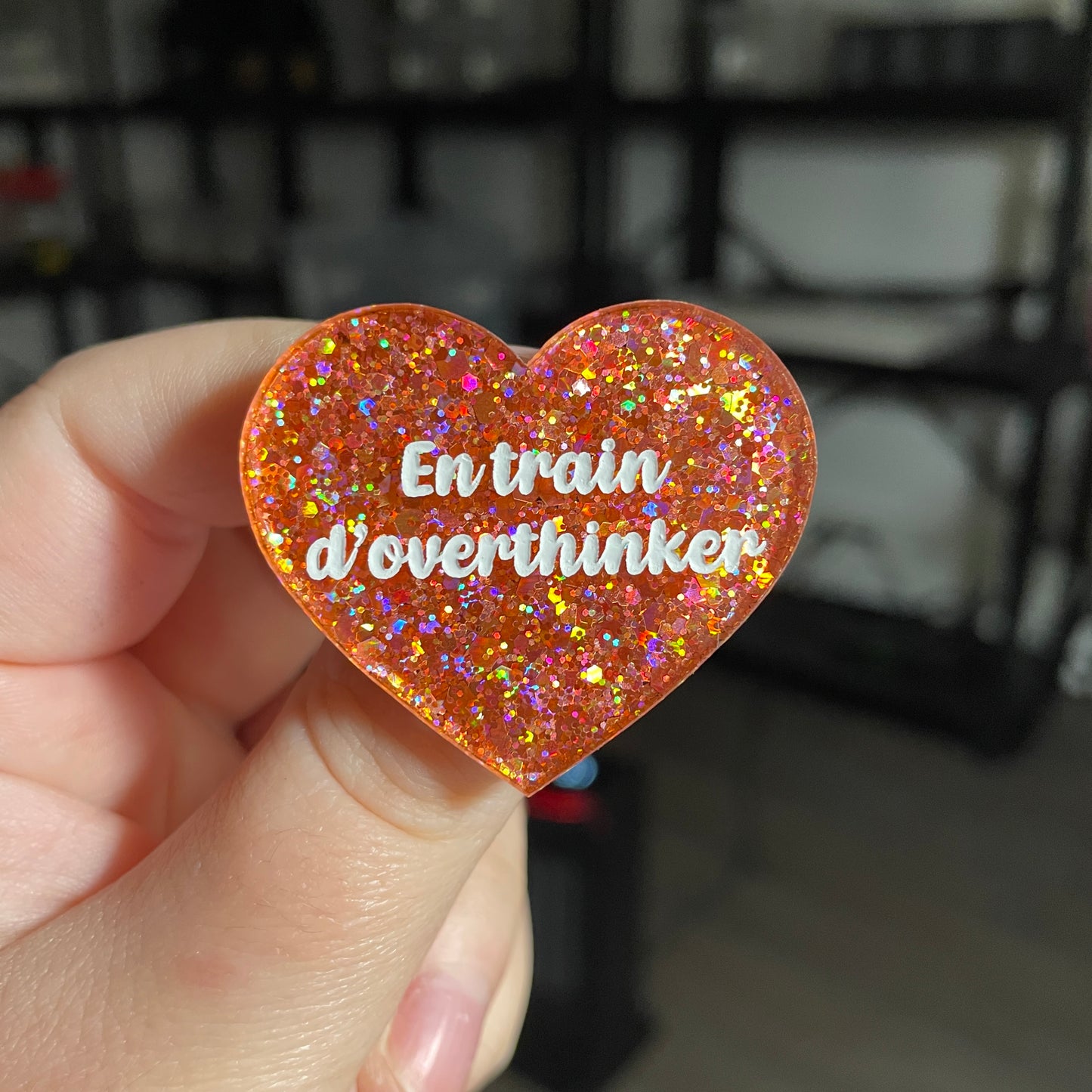 Broche "En train d'overthinker" en acrylique semi transparente avec des paillettes corail