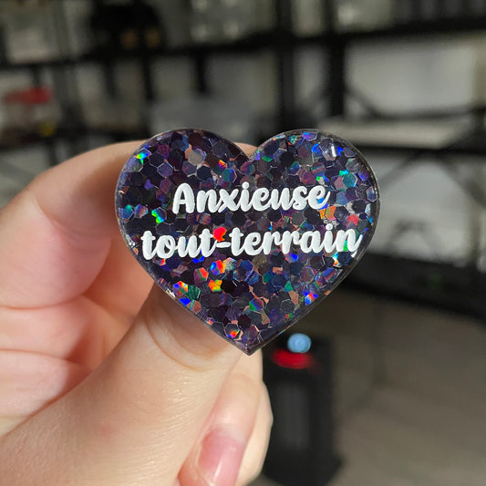 Broche "Anxieuse tout-terrain" en acrylique semi transparente avec des confettis noirs