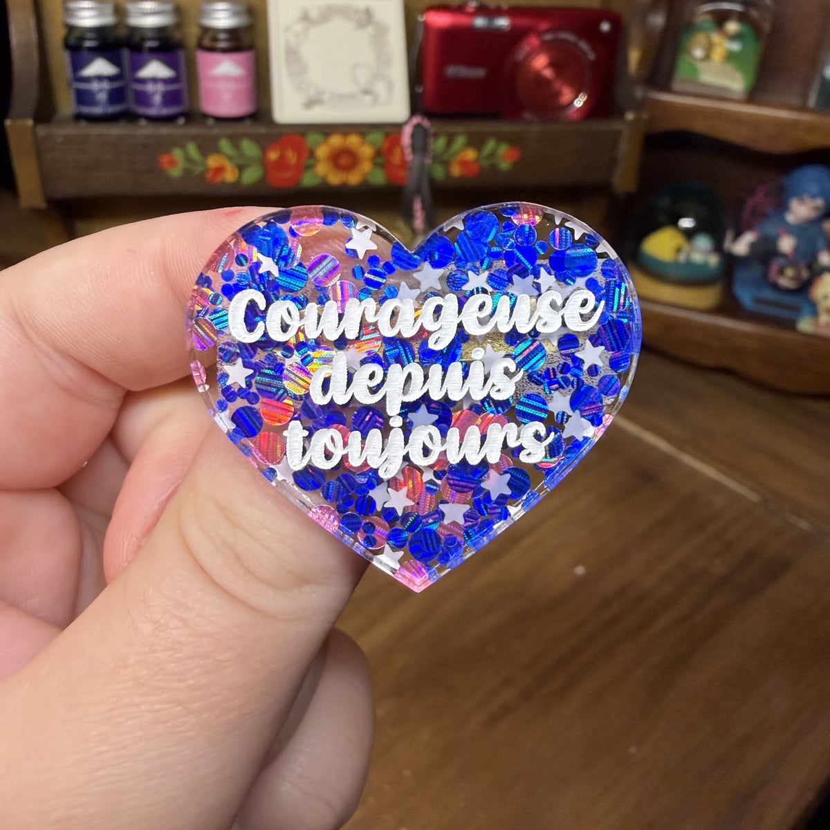 Broche "Courageuse depuis toujours" en acrylique semi transparente avec des confettis bleus, roses et blancs