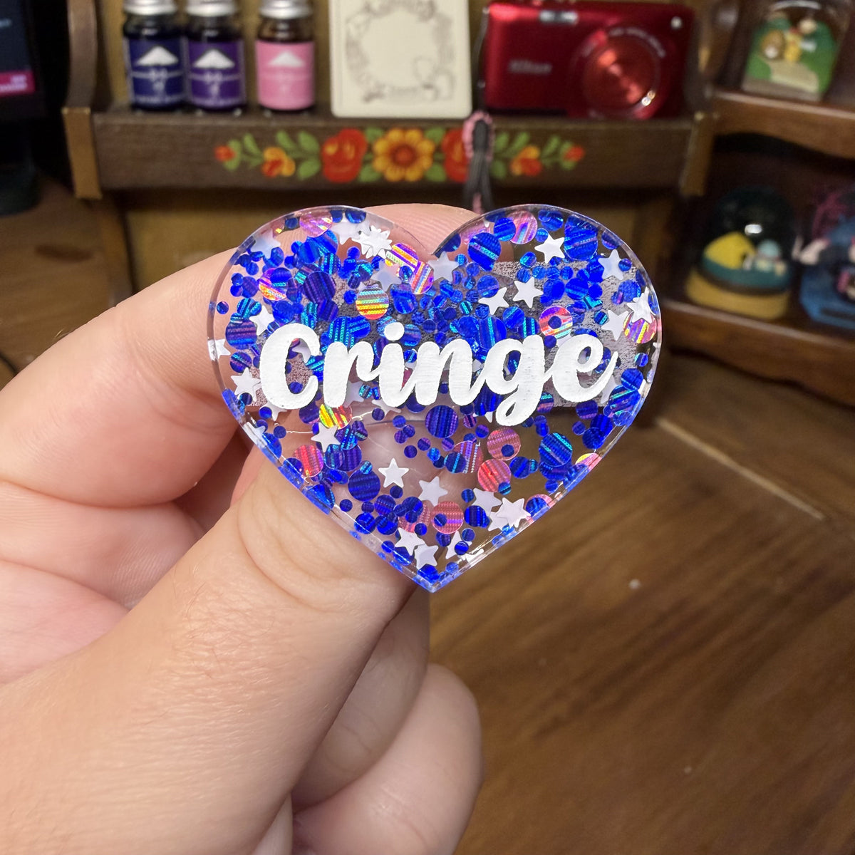 Broche "Cringe" en acrylique semi transparente avec des confettis bleus, roses et blancs