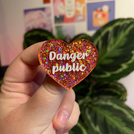 Broche "Danger public" en acrylique semi transparente avec des paillettes corail
