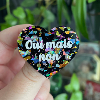 Broche "Oui mais non" en acrylique noire avec des éclats de confettis multicolores