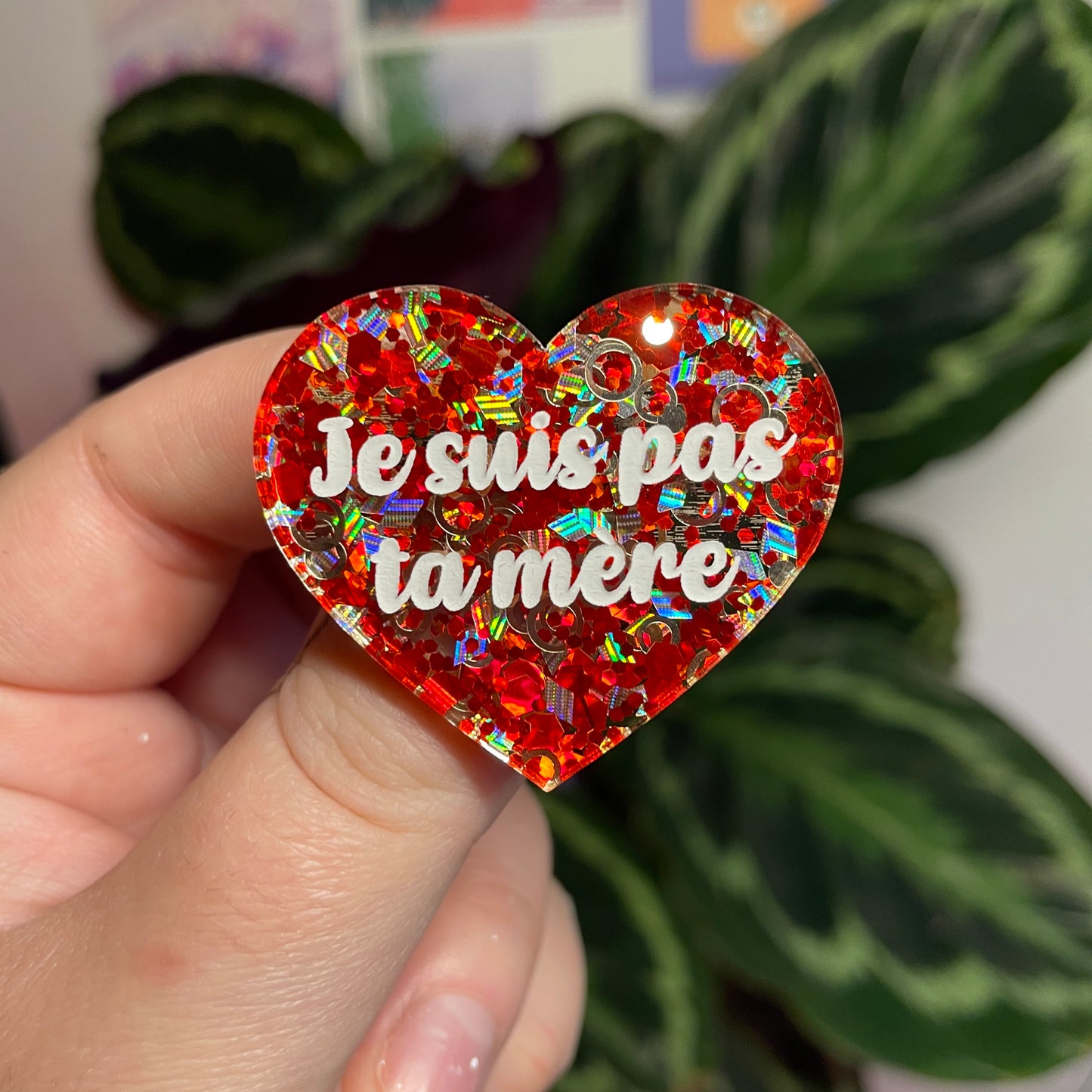 Broche "Je suis pas ta mère" en acrylique semi transparente avec des confettis rouges et argentés