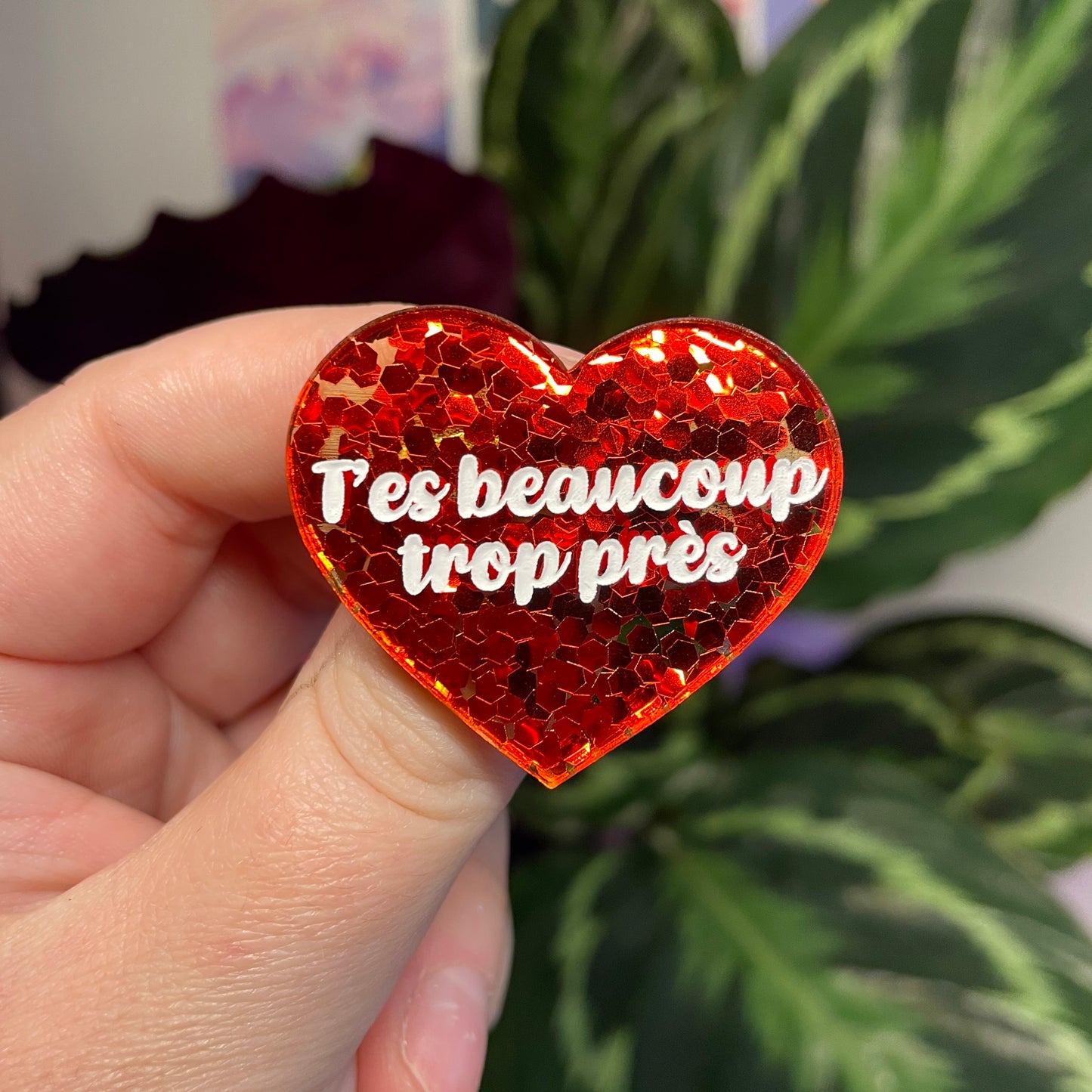 Broche "T'es beaucoup trop près" en acrylique semi transparente avec des confettis rouges