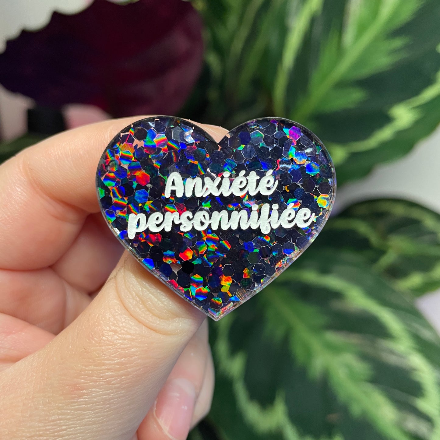 Broche "Anxiété personnifiée" en acrylique semi transparente avec des confettis noirs