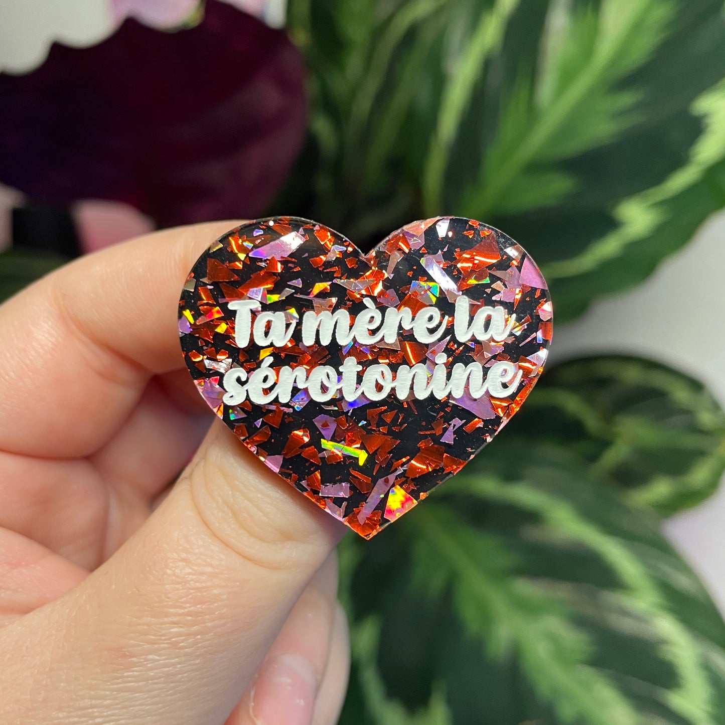 Broche "Ta mère la sérotonine" en acrylique noire avec des éclats de confettis rouges et roses