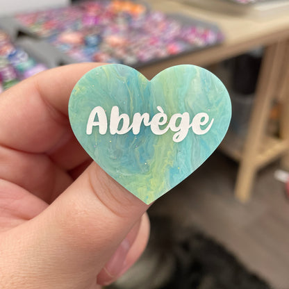 Broche "Abrège" en acrylique marbrée semi-transparente bleue, turquoise, blanche et jaune à paillettes