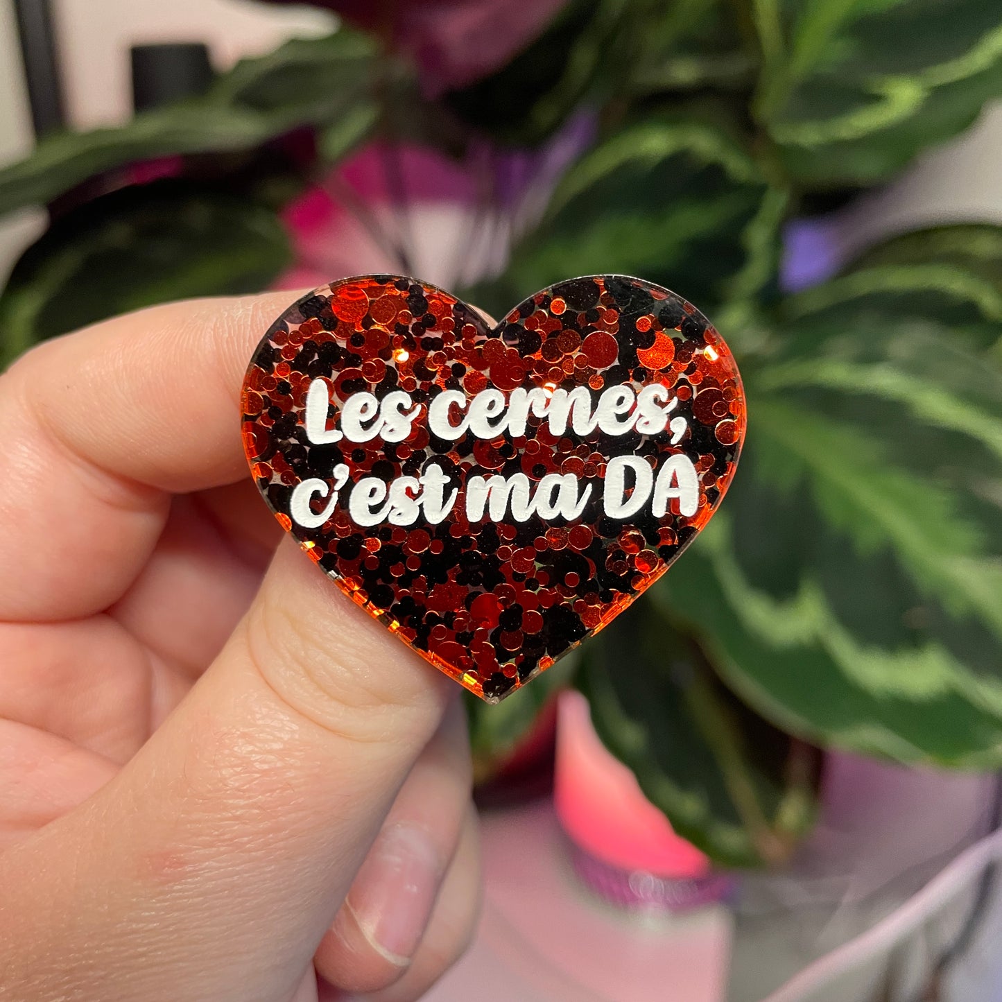 Broche "Les cernes, c'est ma DA" en acrylique semi transparente avec des pois rouges et noirs