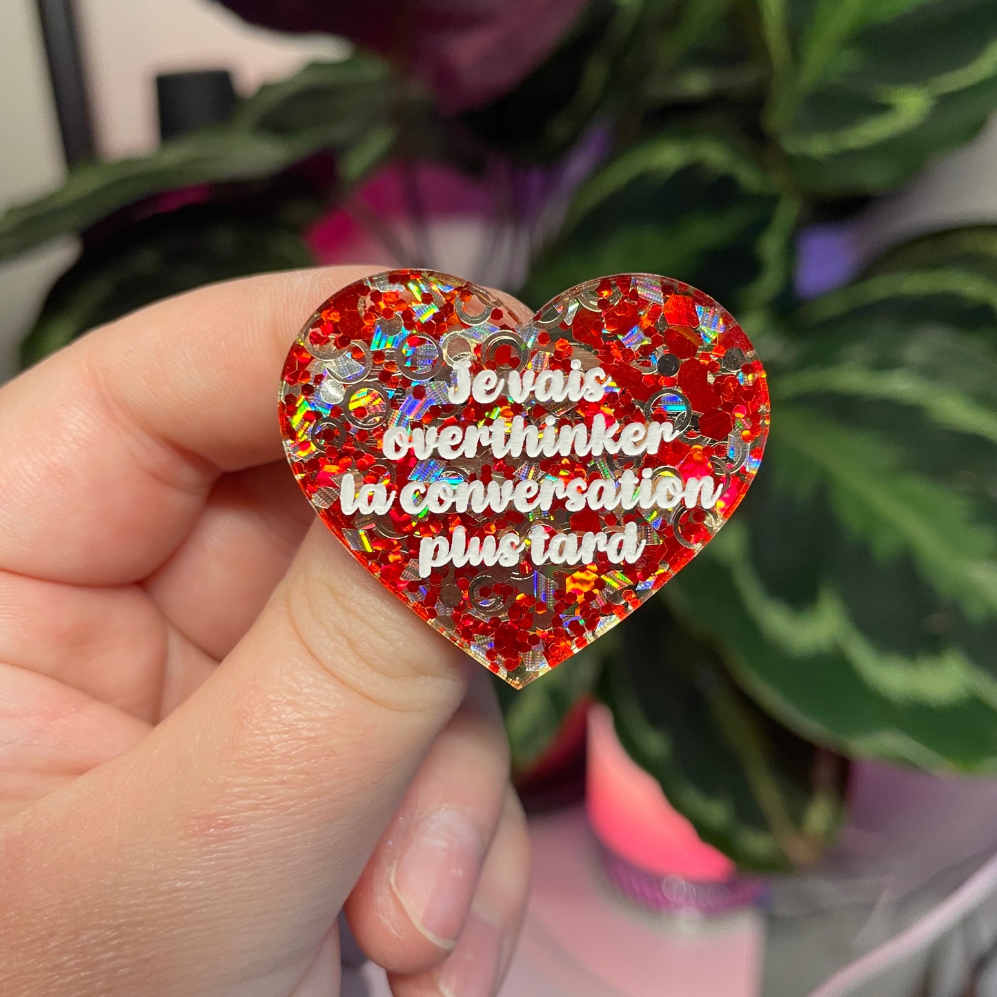 Broche "Je vais overthinker la conversation plus tard" en acrylique semi transparente avec des confettis rouges et argentés