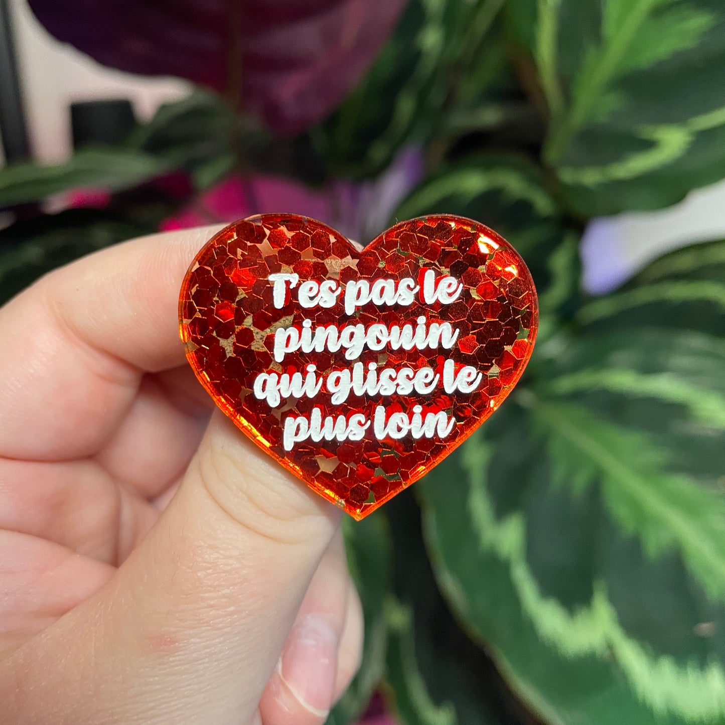 Broche "T'es pas le pingouin qui glisse le plus loin" en acrylique semi transparente avec des confettis rouges
