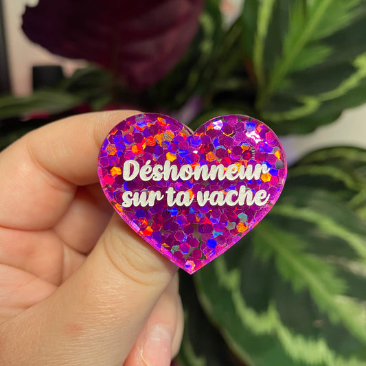Broche "Déshonneur sur ta vache" en acrylique semi transparente avec des confettis fuchsia