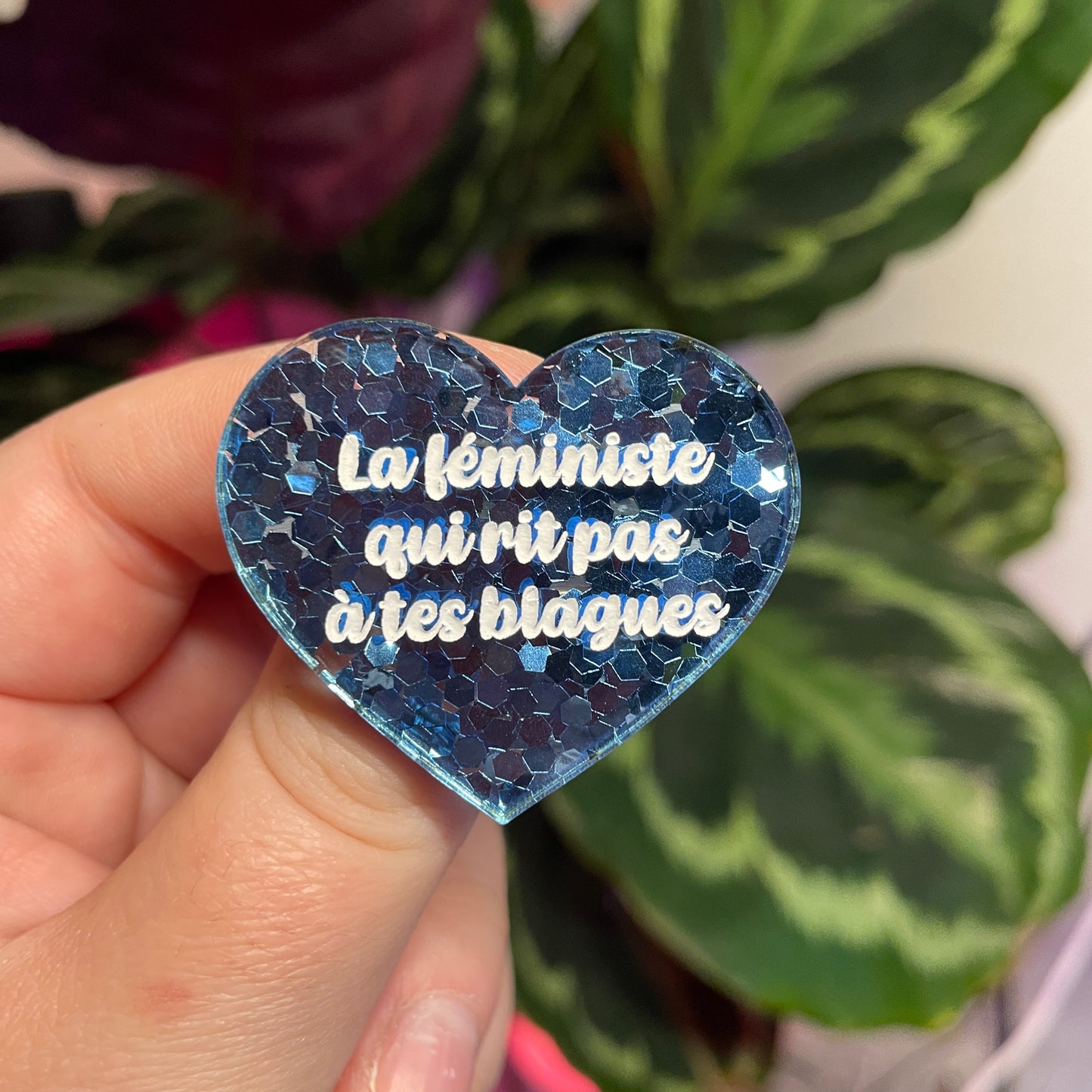 Broche "La féministe qui rit pas à tes blagues" en acrylique semi transparente avec des confettis bleus