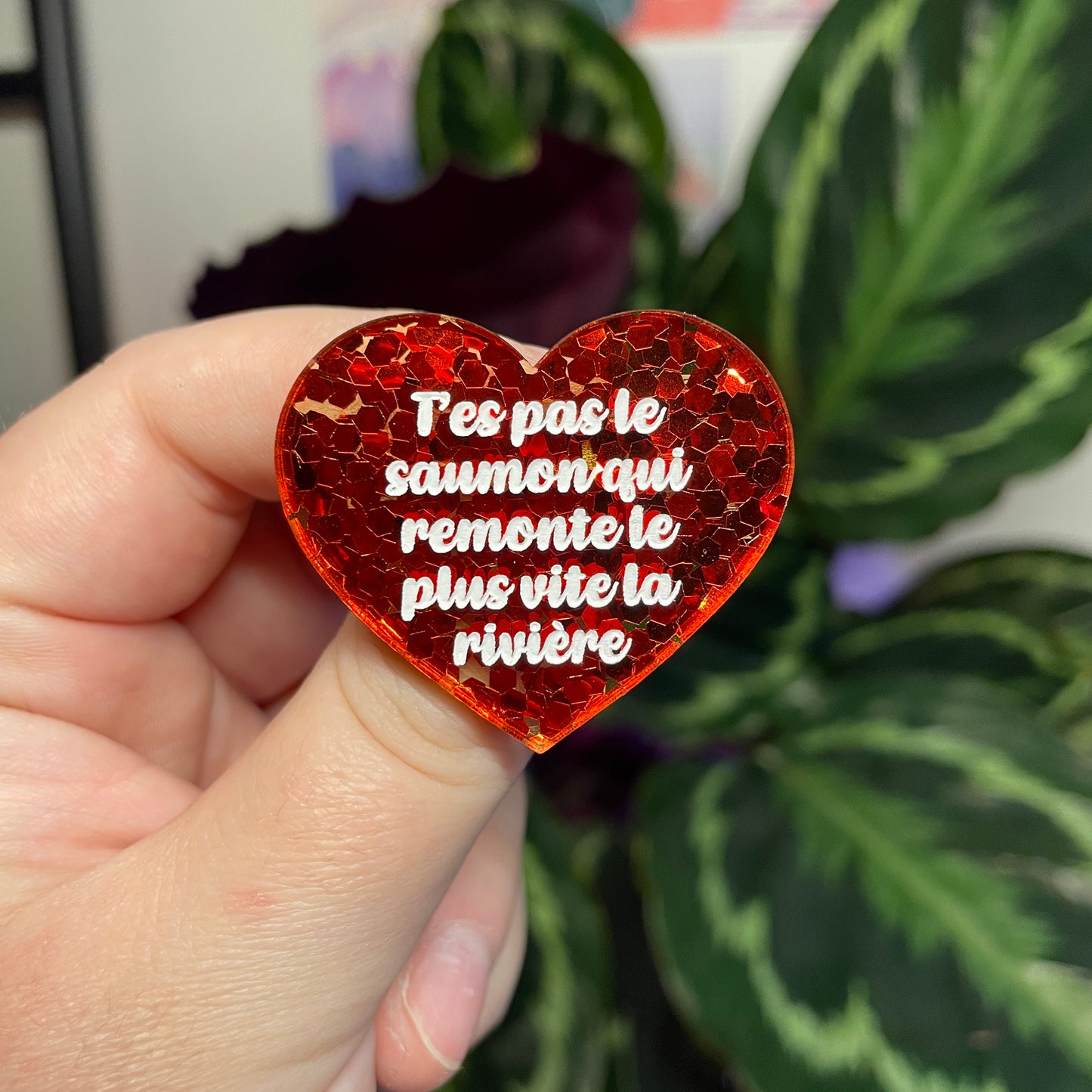 Broche "T'es pas le saumon qui remonte le plus vite la rivière" en acrylique semi transparente avec des confettis rouges