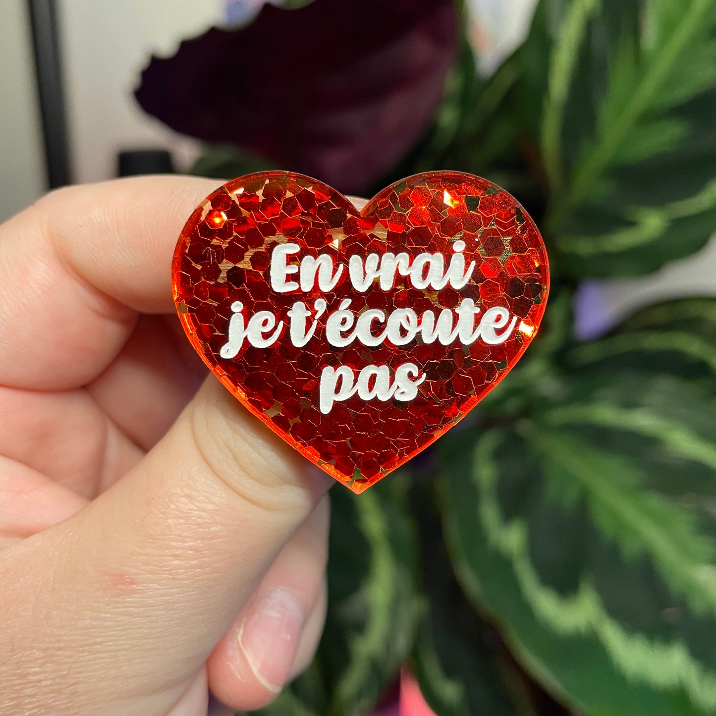 Broche "En vrai je t'écoute pas" en acrylique semi transparente avec des confettis rouges