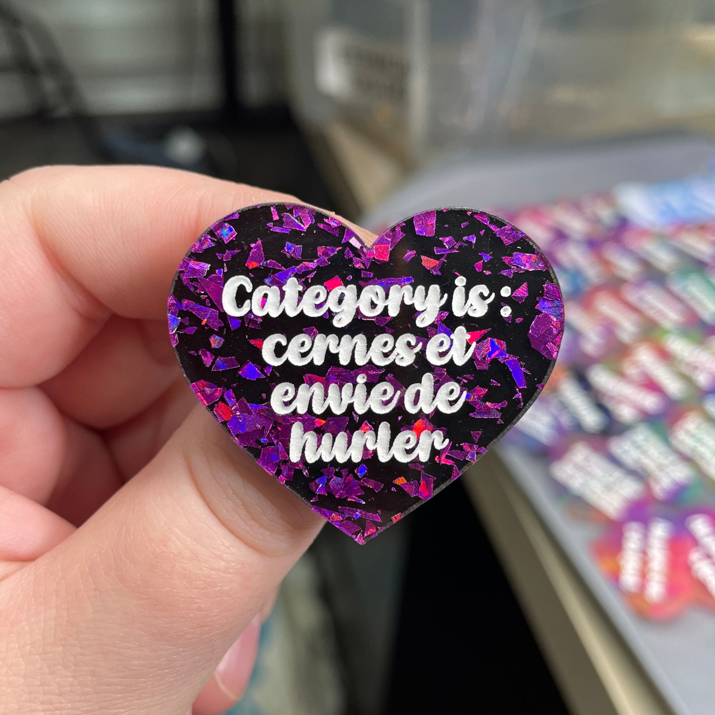 Broche "Category is : cernes et envie de hurler" en acrylique noire avec des éclats de confettis violets