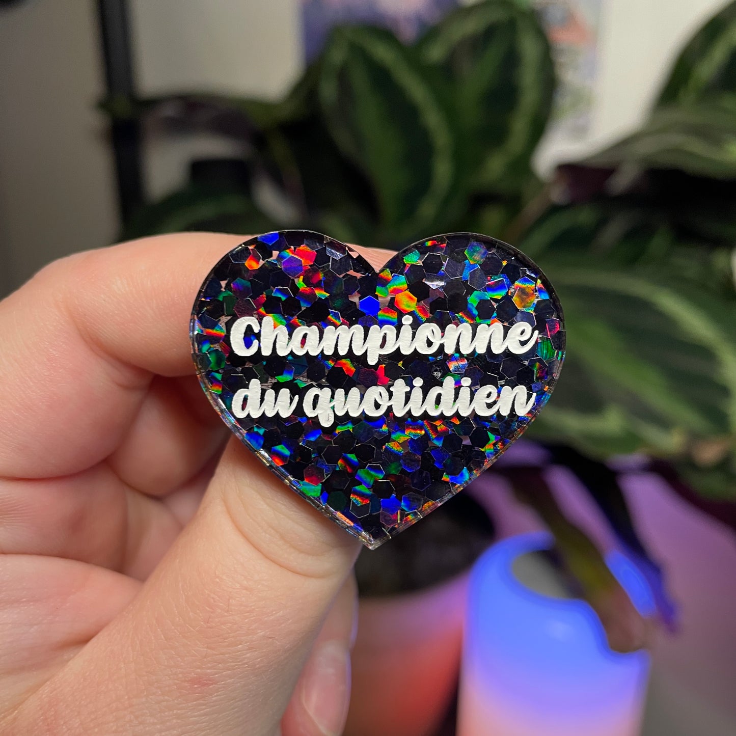 Broche "Championne du quotidien" en acrylique semi transparente avec des confettis noirs