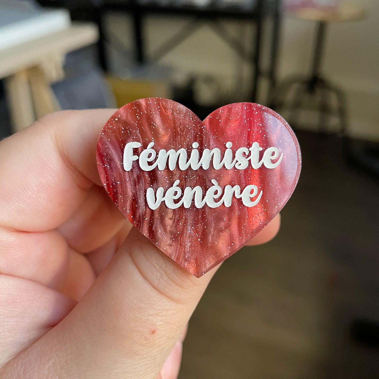Broche "Féministe vénère" en acrylique marbrée rouge, marron et blanche à paillettes