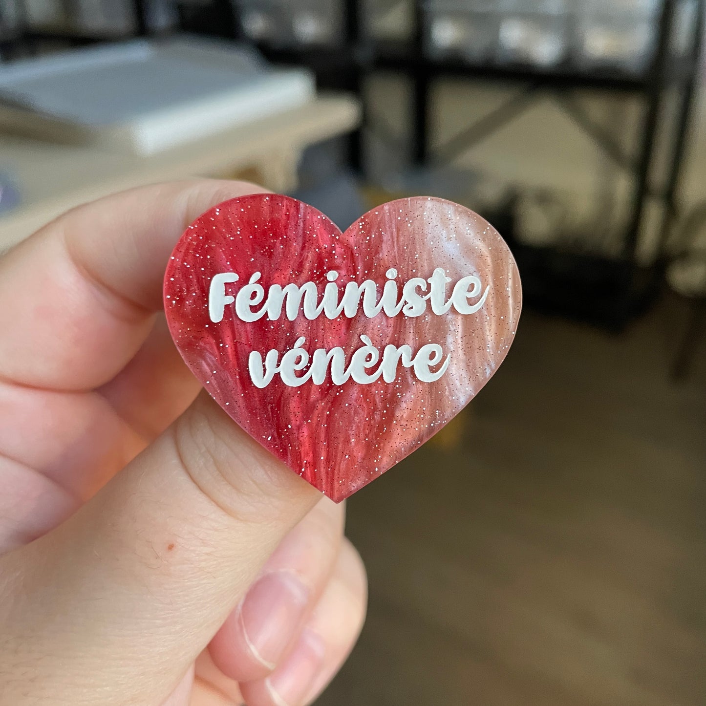 Broche "Féministe vénère" en acrylique marbrée rouge, marron et blanche à paillettes