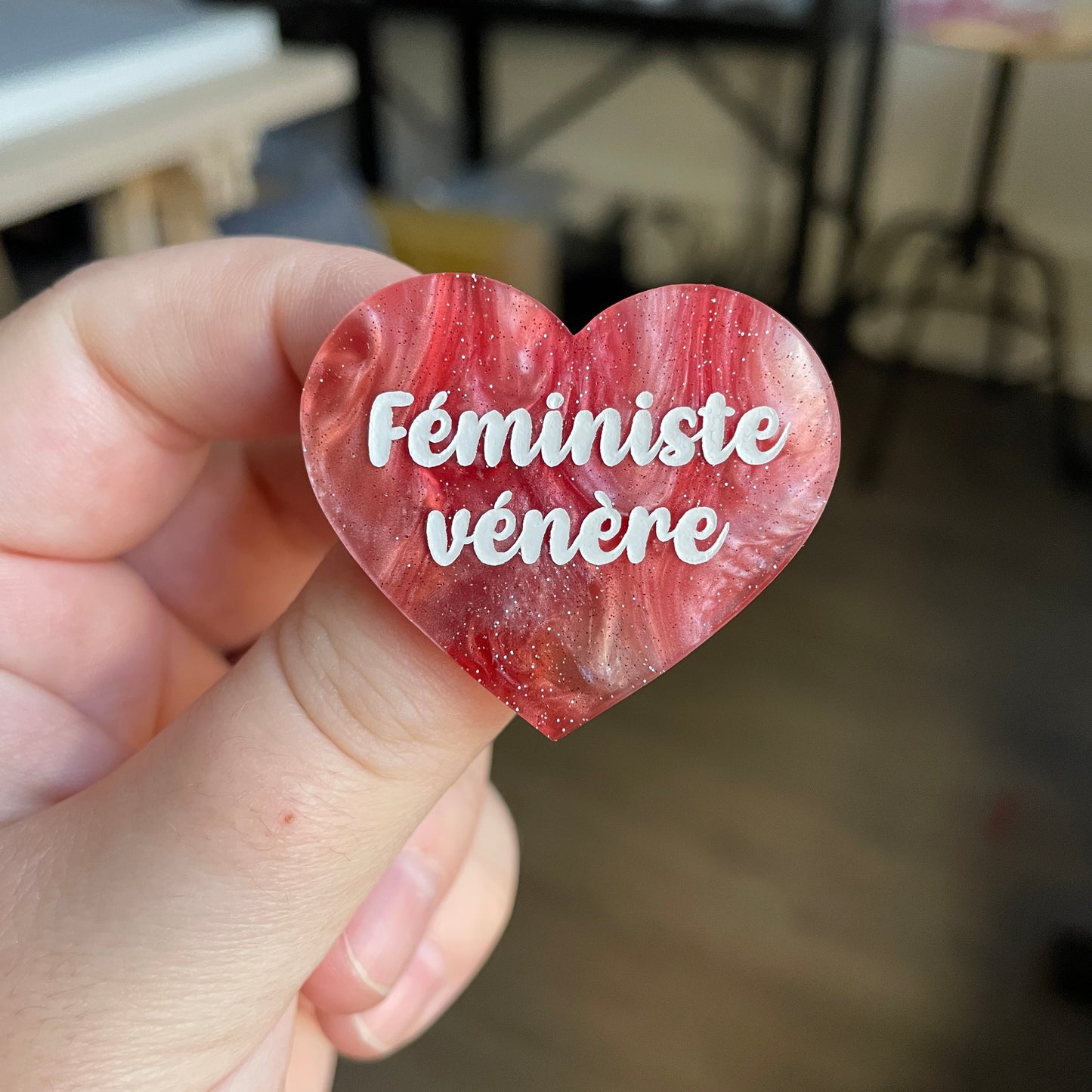Broche "Féministe vénère" en acrylique marbrée rouge, marron et blanche à paillettes