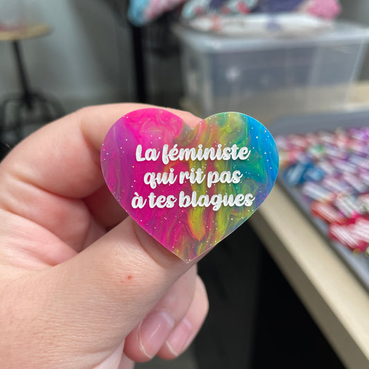 Broche "La féministe qui rit pas à tes blagues" en acrylique semi-transparente marbrée multicolore