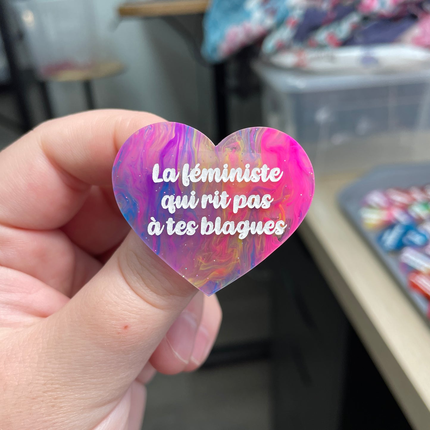 Broche "La féministe qui rit pas à tes blagues" en acrylique semi-transparente marbrée multicolore