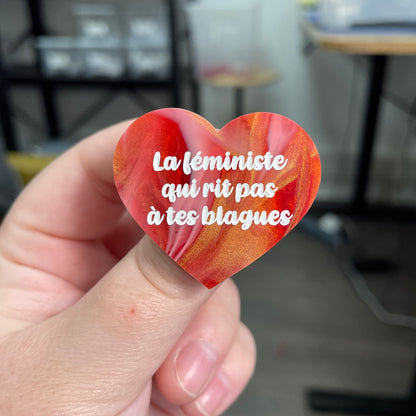 Broche "La féministe qui rit pas à tes blagues" en acrylique marbrée rouge, blanche et dorée