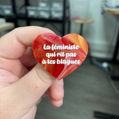 Broche "La féministe qui rit pas à tes blagues" en acrylique marbrée rouge, blanche et dorée
