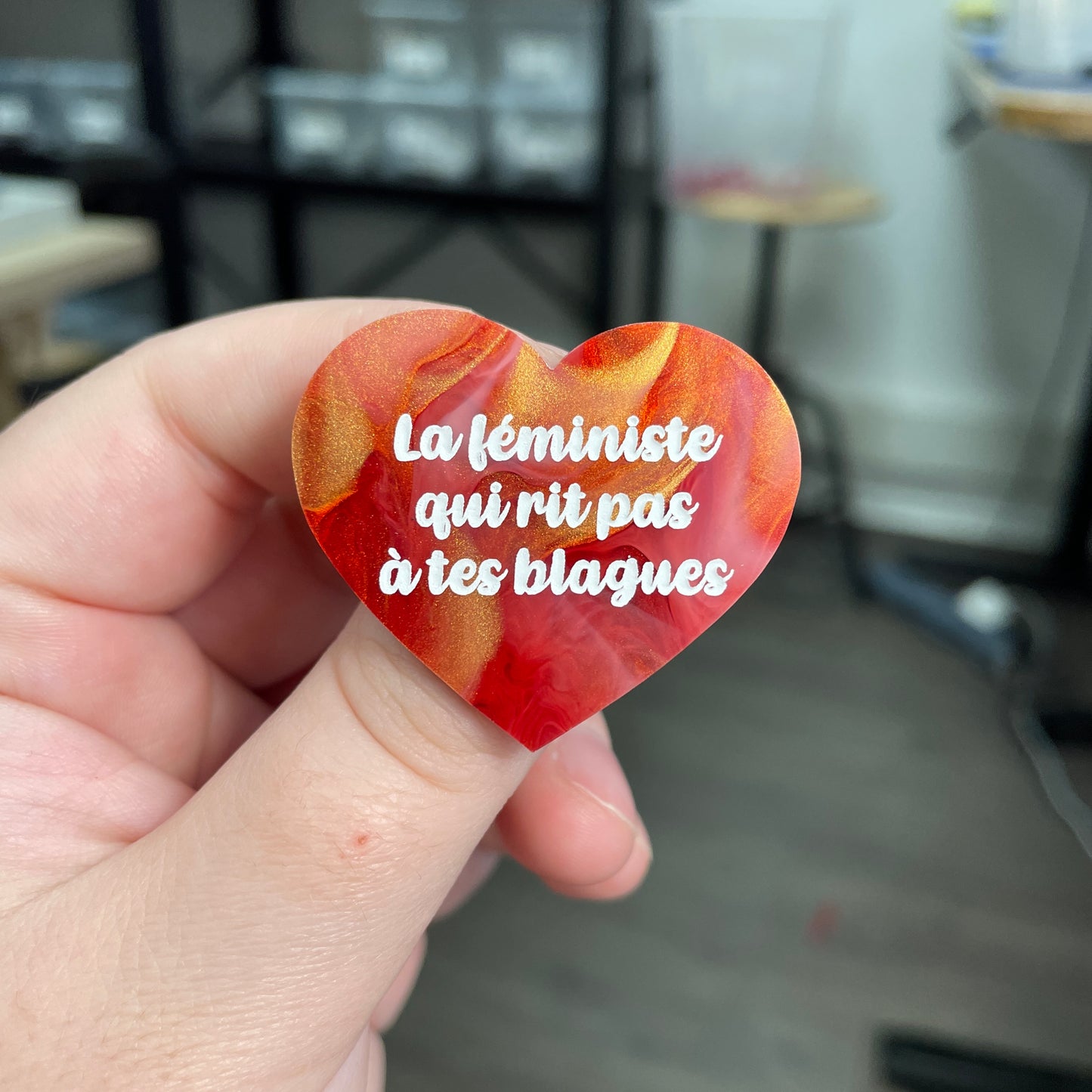 Broche "La féministe qui rit pas à tes blagues" en acrylique marbrée rouge, blanche et dorée