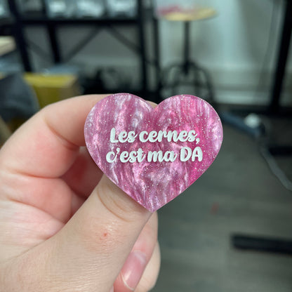 Broche "Les cernes, c'est pas DA" en acrylique marbrée rose et blanche à paillettes