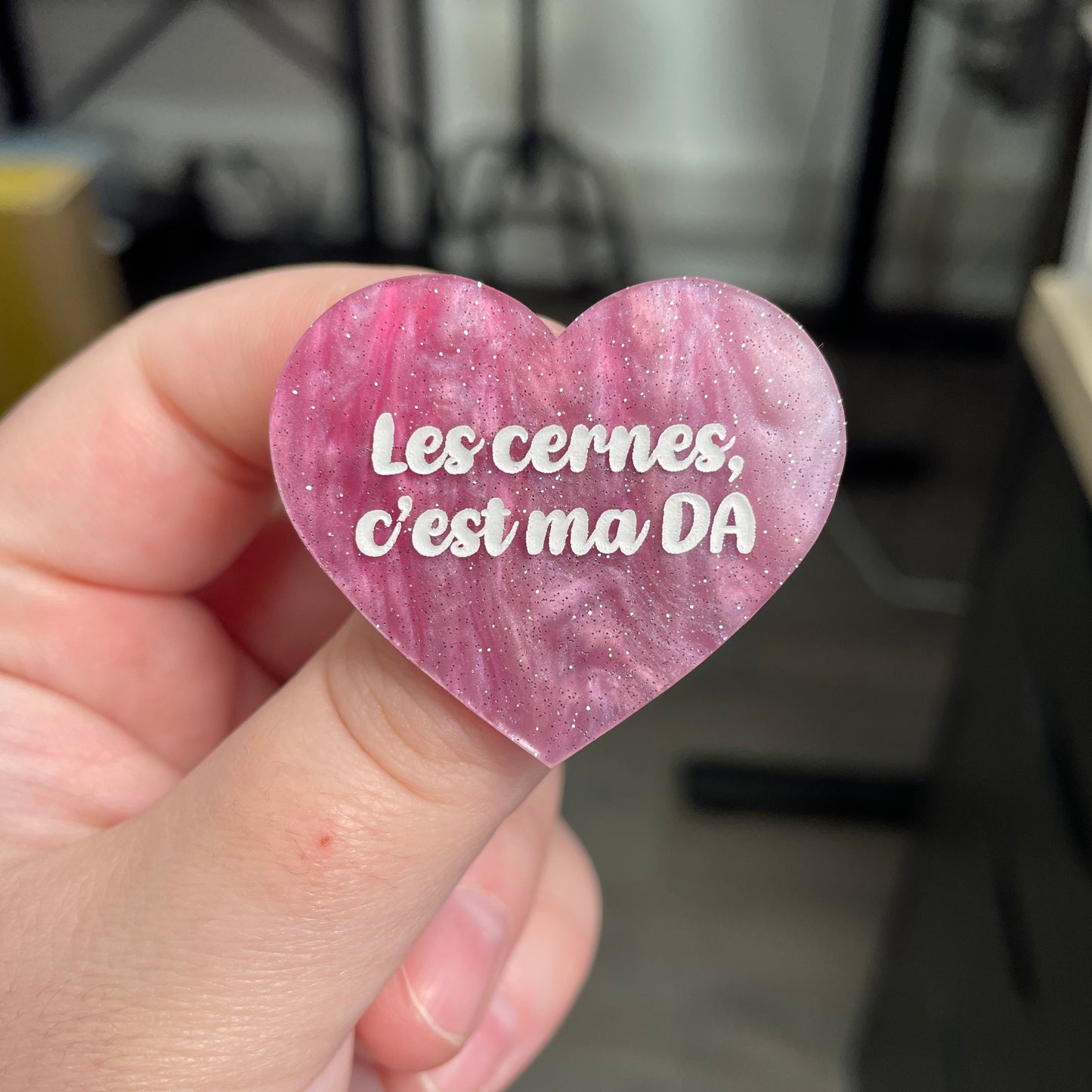 Broche "Les cernes, c'est pas DA" en acrylique marbrée rose et blanche à paillettes