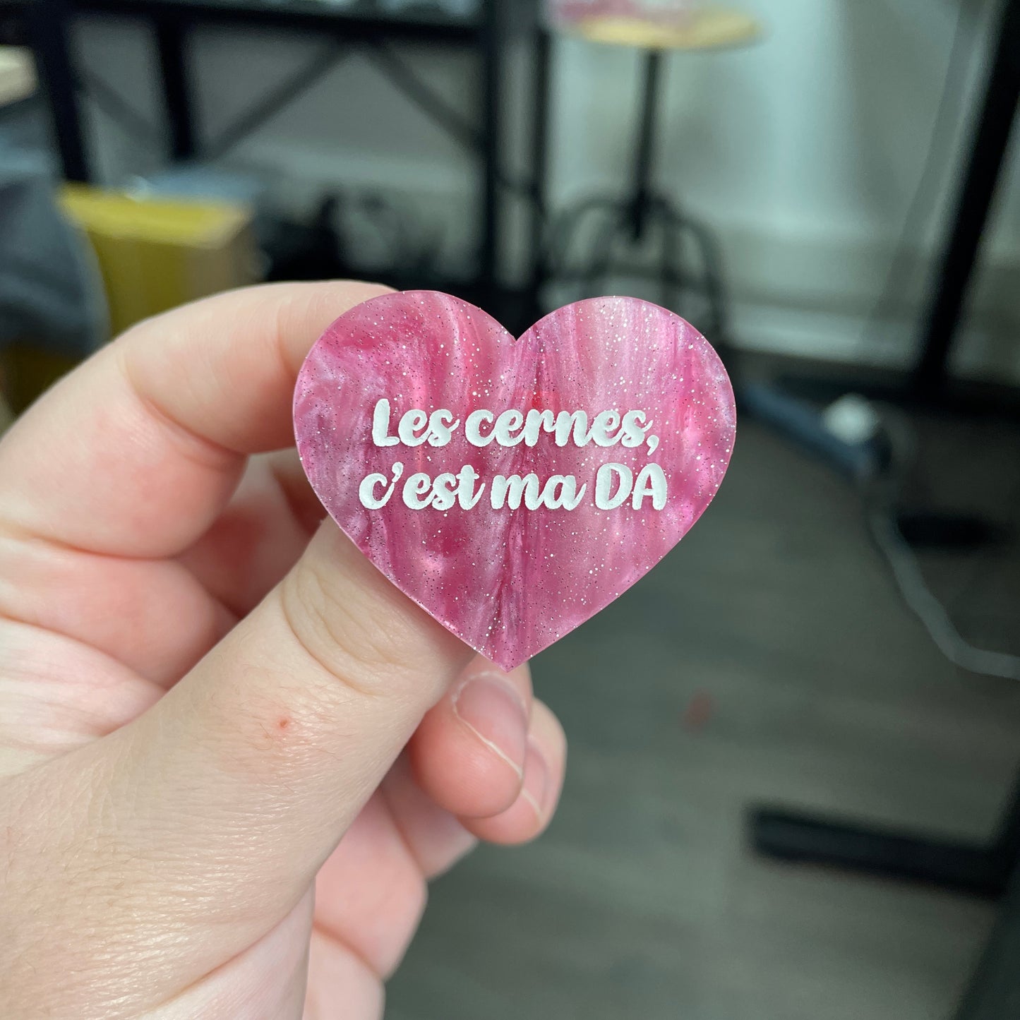 Broche "Les cernes, c'est pas DA" en acrylique marbrée rose et blanche à paillettes