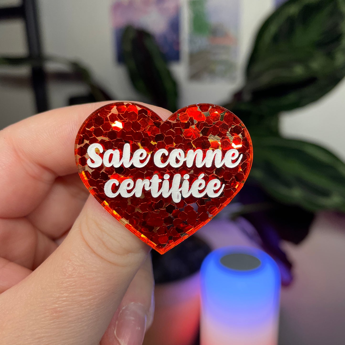 Broche "Sale conne certifiée" en acrylique semi transparente avec des confettis rouges