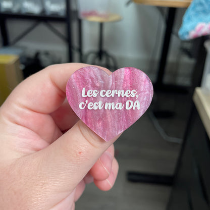 Broche "Les cernes, c'est pas DA" en acrylique marbrée rose et blanche à paillettes