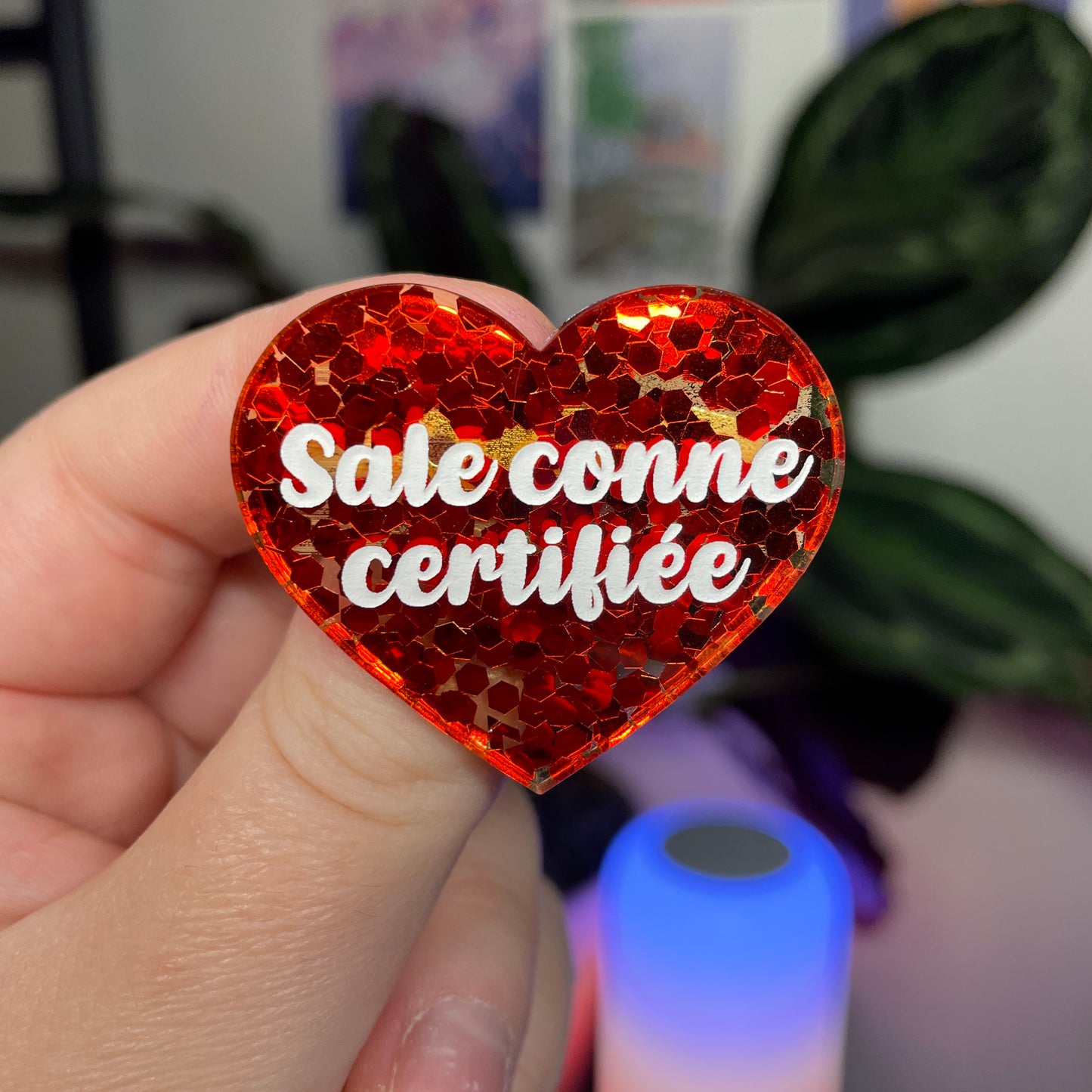 Broche "Sale conne certifiée" en acrylique semi transparente avec des confettis rouges