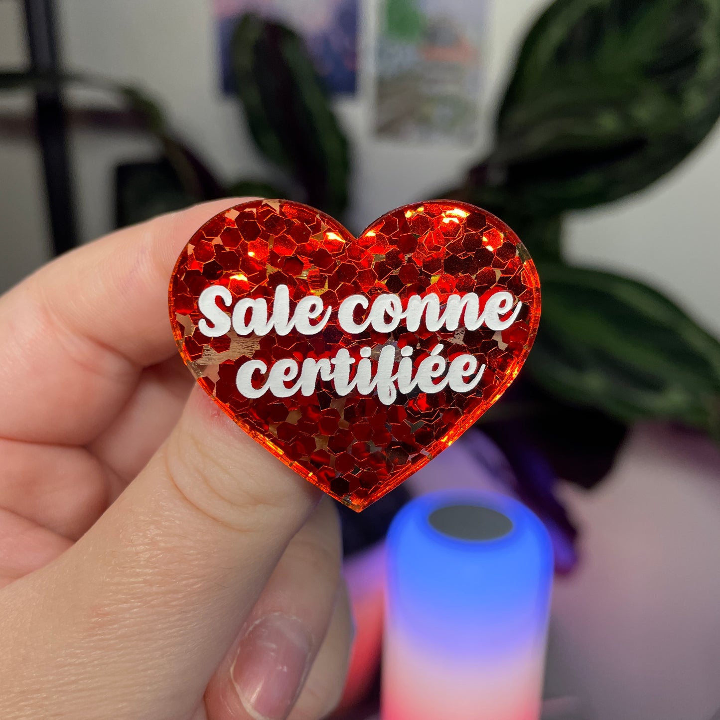 Broche "Sale conne certifiée" en acrylique semi transparente avec des confettis rouges