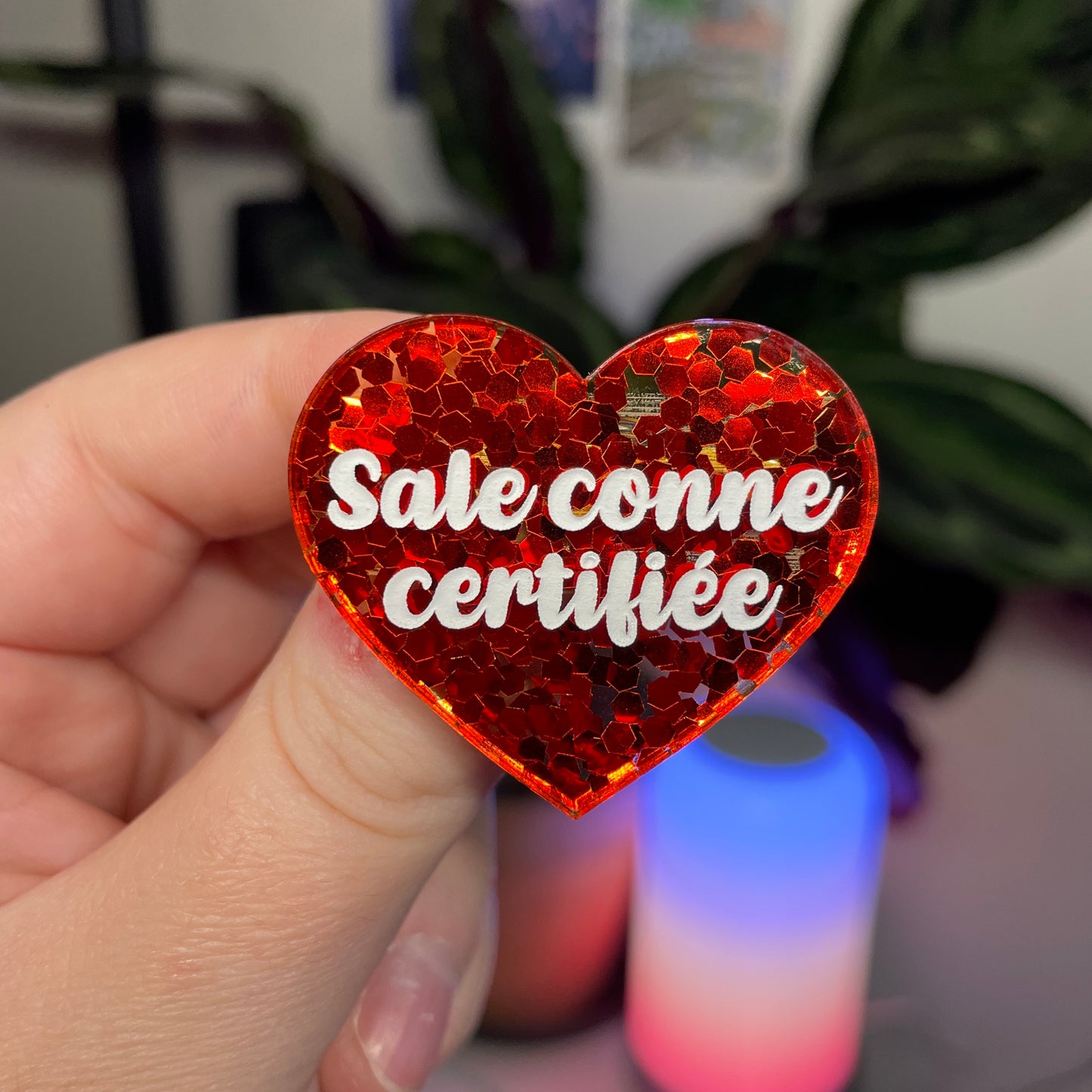 Broche "Sale conne certifiée" en acrylique semi transparente avec des confettis rouges